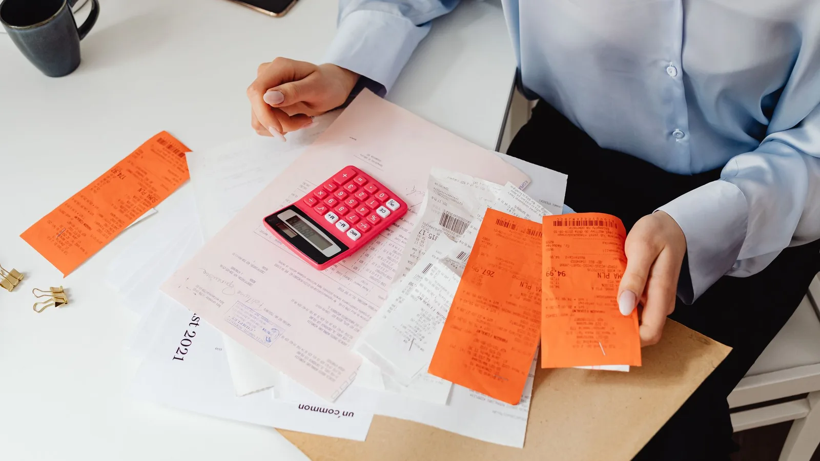 Una persona revisa recibos y documentos con una calculadora.